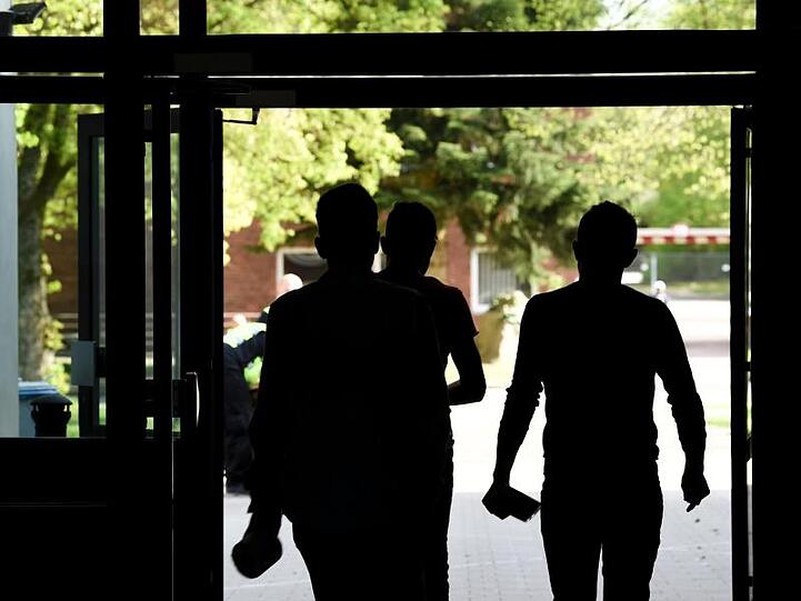 Drei Asylbewerber laufen aus einem Gebäude der Landeserstaufnahmeeinrichtung hinaus.