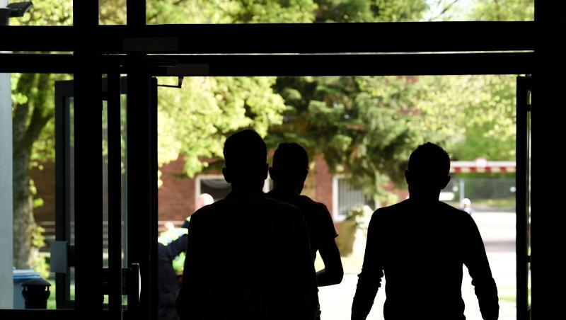 Drei Asylbewerber laufen aus einem Gebäude der Landeserstaufnahmeeinrichtung hinaus. Drei Asylbewerber laufen aus einem Gebäude der Landeserstaufnahmeeinrichtung hinaus.