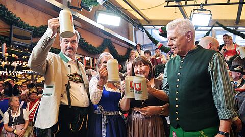 Bayerns Ministerpräsident Söder (l.) und Münchens OB Reiter (r.) stoßen mit ihren Ehefrauen auf eine friedliche Wiesn an.