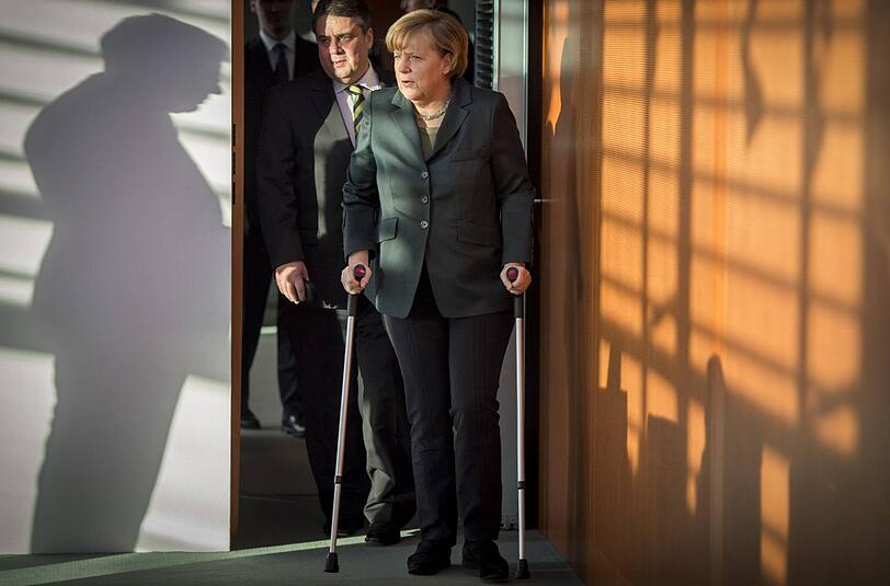 Auf Krücken betritt Kanzlerin Angela Merkel den Kabinetts-Saal. Vizekanzler Sigmar Gabriel trägt ihr die Papiere.