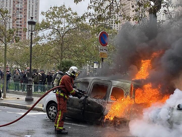 Ein Feuerwehrmann löscht in Paris ein von "Gelbwesten" in Brand gesetztes Auto.