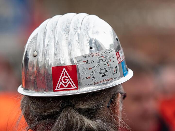 Das Logo der IG Metall befindet sich auf dem Helm eines Stahlarbeiters. Foto: Bernd Thissen/dpa/Archivbild