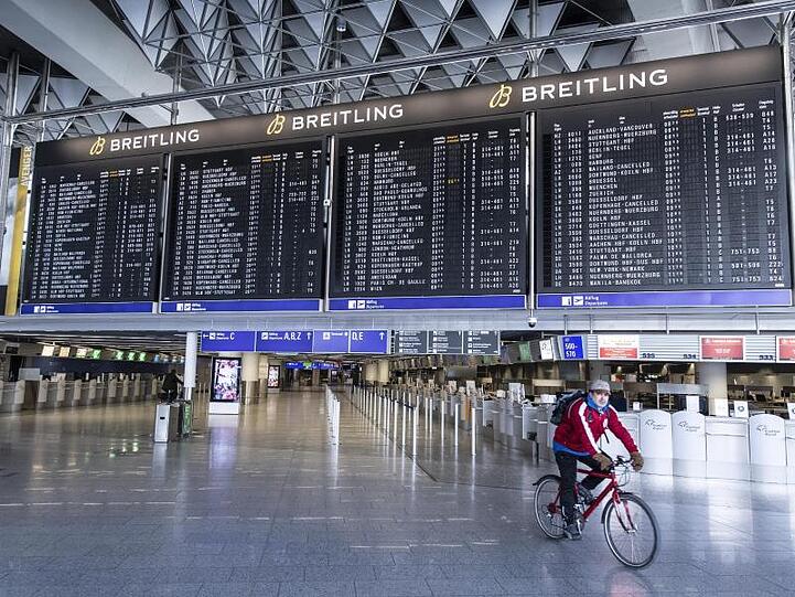 Auf einem Fahrrad fährt ein Mann durch das ansonsten menschenleere Terminal 1 des Flughafens Frankfurt.