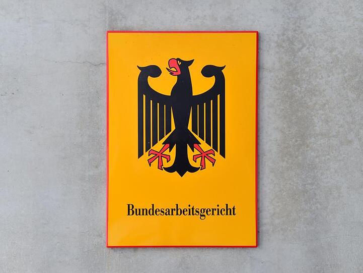 Das Behördenschild des Bundesarbeitsgerichts ist am Eingang des Gebäudes zu sehen. Foto: Martin Schutt/Archiv