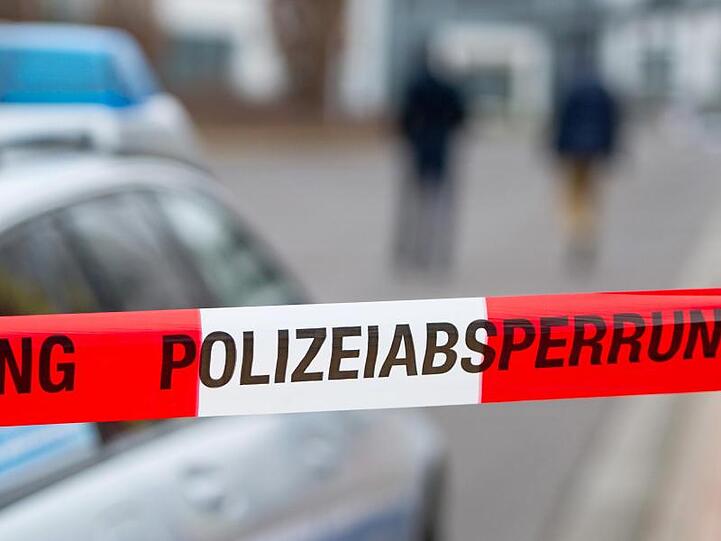 Ein Polizeiabsperrband vor einem Polizeiwagen. Foto: Marc Tirl/ZB/dpa/Symbolbild