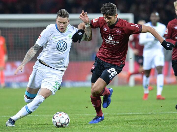 Wolfsburgs Daniel Ginczek (l) und Nürnbergs Lukas Mühl kämpfen im Max-Morlock-Stadion um den Ball. Foto: Timm Schamberger