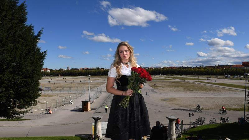 Viktoria Ostler steht im schwarzen Gedenkdirndl mit einem Strauß rote Rosen auf den Stufen vor der Bavaria.