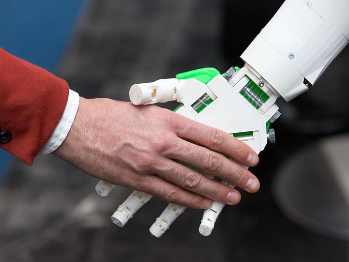 Ein humanoider Roboter gibt einem Menschen die Hand am Stand von ioX Lab bei der IT-Messe CeBIT. Foto: Friso Gentsch/Archiv