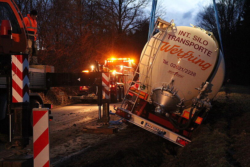 Ein Bergungsfahrzeug und zwei Kräne werden benötigt um den vollbeladenen LKW wieder auf die Straße zu ziehen.