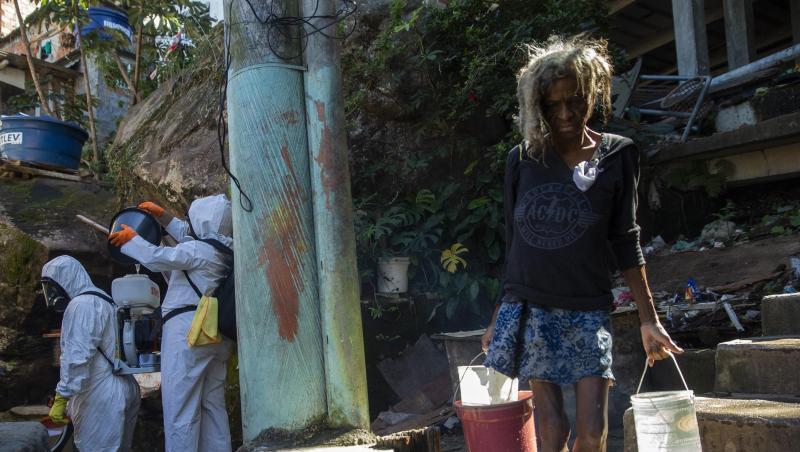 Eine Bewohnerin in einer Favela in Rio de Janeiro holt Wasser, während Freiwillige versuchen das Viertel zu desinfizieren. Eine Bewohnerin in einer Favela in Rio de Janeiro holt Wasser, während Freiwillige versuchen das Viertel zu desinfizieren.