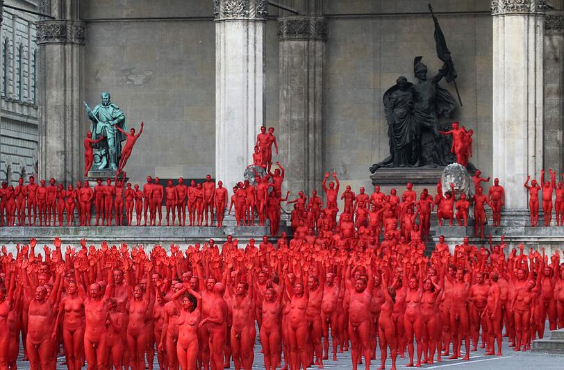 Star-Fotograf Spencer Tunick lässt zur Eröffnung der Opernfestspiele für seine Installation hunderte bunt angemalte Menschen durch München laufen. Das Highlight: Die rot-goldenen Teilnehmer stellen sich an Münchner Monumenten entlang der Ludwigstraße auf. Hier gibts die Bilder!