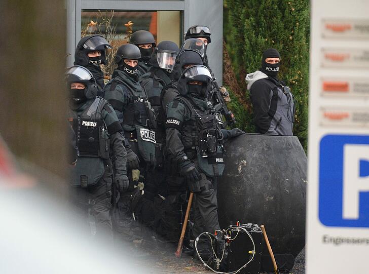 Mit erhobenen Händen kommt ein Mann auf die SEK-Beamten zu, im Hintergrund lauern Heckenschützen der Polizei. Die Beamten nehmen den Mann fest, es ist aber nicht der Täter, der sich in einem Imbiss in Freiburg veschanzt hat.