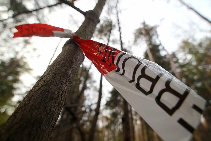 Mehr als 200 Menschen nahmen an der Gedenkfeier für dem ermordeten Augsburger Polizisten teil: Sie hatten zu einem Schweigemarsch vom Stauwehr Hochablass bis zum Tatort im Waldgebiet Siebentischwald zusammengefunden, wo der Mann am Freitag erschossen worden war. Absperrbänder kennzeichnen den Tatort.