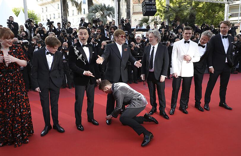 Taron Egerton bindet die Schnürsenkel von Elton John am Roten Teppich.