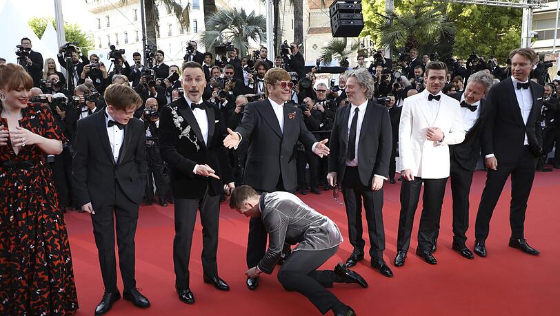 Taron Egerton bindet die Schnürsenkel von Elton John am Roten Teppich. Taron Egerton bindet die Schnürsenkel von Elton John am Roten Teppich.