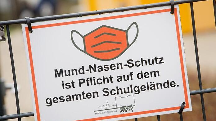 Ein Schild weist an einer Schule auf die Maskenpflicht hin.