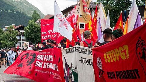 Demonstranten tragen Banner am Rand der Demonstration gegen den G7 Gipfel.