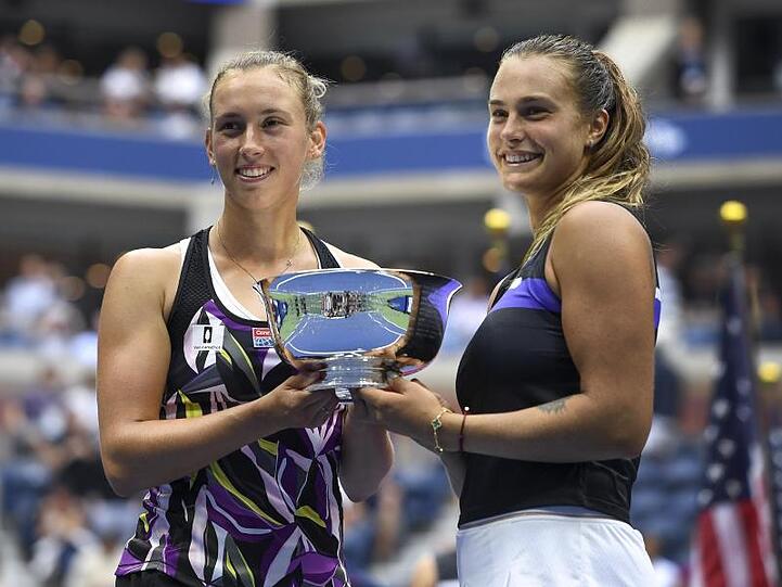 Aryna Sabalenka (r) und Elise Mertens halten nach ihrem Sieg im Doppel bei den US Open die Trophäe in den Händen.