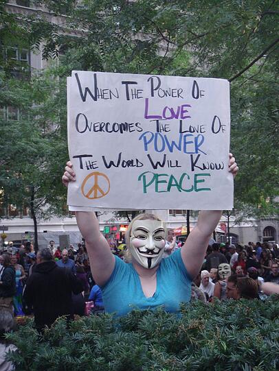 "Wenn die Macht der Liebe die Liebe zur Macht überwindet, wird die Welt Frieden kennen", steht auf dem Protest-Plakat dieser Frau.