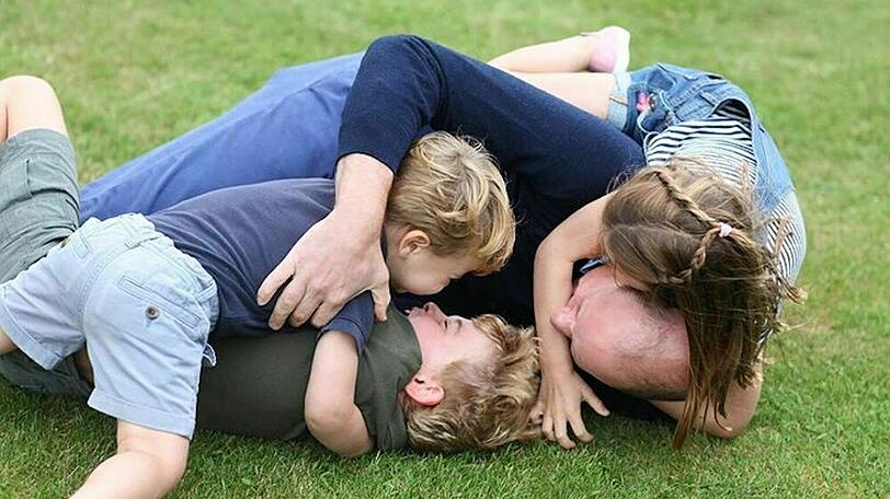Prinz William tobt mit seinen drei Kindern im Gras.