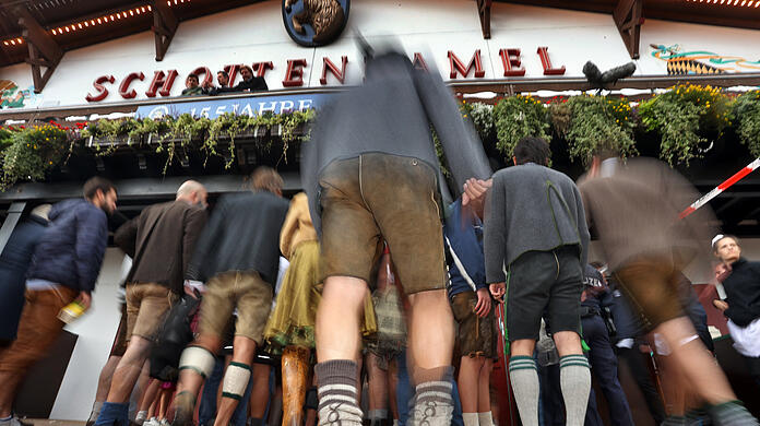 Oktoberfestbesucher in bayerischer Tracht stehen vor einem dem Schottenhamel-Festzelt.