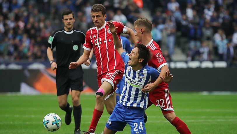 Thomas Müller (l.) und Joshua Kimmich (r.) käpfen mit Herthas Genki Haraguchi um den Ball. Thomas Müller (l.) und Joshua Kimmich (r.) käpfen mit Herthas Genki Haraguchi um den Ball.