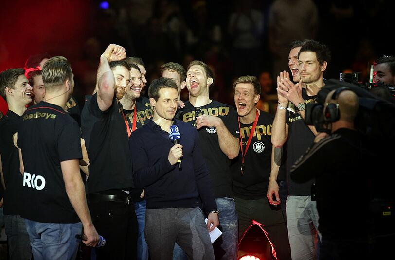 Die deutschen Handball-Nationalspieler Rune Dahmke (l-r), Nationaltorwart Andreas Wolff, Kai Haefner, Steffen Weinhold, Niclas Pieczkowski, Erik Schmidt und Nationaltorwart Carsten Lichtlein stehen am 01.02.21016 mit Moderator Alexander Bommes (M) bei einem Fan-Fest in der Max-Schmeling-Halle in Berlin auf der Bühne.