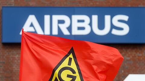 Eine Fahne der IG-Metall weht bei einem Warnstreik vor dem Schriftzug "Airbus".