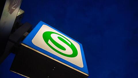 Ein S-Bahn-Schild hängt vor einem dunklen Morgenhimmel. Foto: Lino Mirgeler/dpa/Archivbild