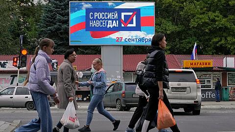 Menschen gehen an einer Anzeige mit der Aufschrift "Für immer mit Russland" in Luhansk vorbei.