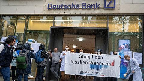 Aktivisten nehmen vor und in einer Filiale der Deutschen Bank in der bayerischen Landeshauptstadt an einer Protestaktion der "Scientist Rebellion Deutschland" teil.