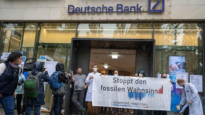 Aktivisten nehmen vor und in einer Filiale der Deutschen Bank in der bayerischen Landeshauptstadt an einer Protestaktion der "Scientist Rebellion Deutschland" teil.