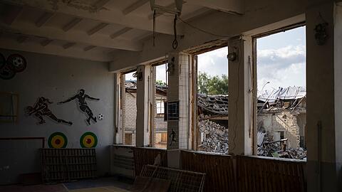 In Kupjansk ist durch die zerbrochenen Fenster einer Turnhalle die zerstörte Bibliothek einer Schule zu sehen.