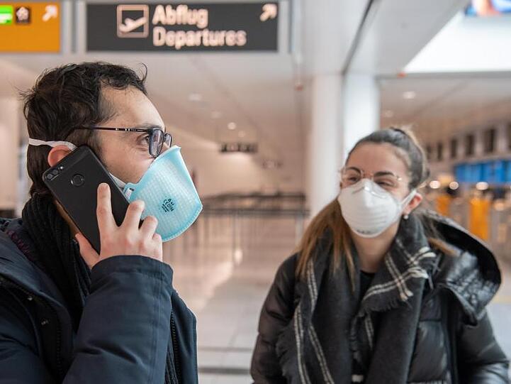 Ein Paar mit Mundschutz wartet auf dem Flughafen München auf den Flug in die Heimat - ins italienische Verona.