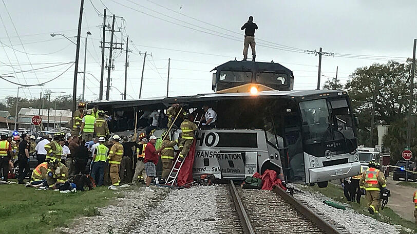 Feuerwehrleute helfen verletzten Passagieren aus einem verunfallten Reisebus, nachdem der Bus am 07.03.2017 in Biloxi (USA) mit einem Zug kollidiert ist.