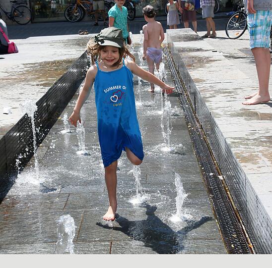 Mia (5) freut sich über eine Abkühlung im Brunnen.