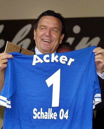 Präsent für den Kanzler: Beim Besuch in der Kleingartenanlage "Bismarckhain" in Gelsenkirchen im Jahr 2004 bekommt Schröder ein Schalke-Trikot mit seinem Fußballer-Spitznamen "Acker".