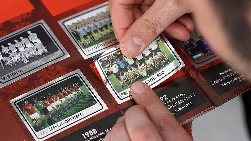 Ein Fußball-Sticker mit dem Foto der deutschen Nationalmannschaft von 1980 wird in ein Panini-Album geklebt. (Archivbild)