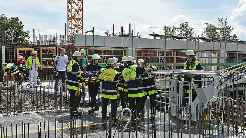 Einsatzkräfte der Feuerwehr transportieren den verletzten Arbeiter ab.