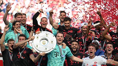 Bayerns Torhüter Manuel Neuer (M) hält die Meisterschale während seine Teamkollegen jubeln.