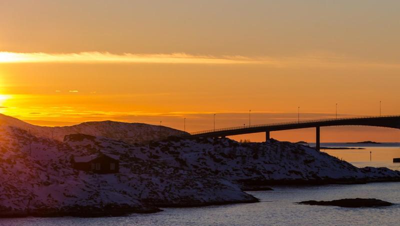 Die Sonne geht hinter der Sommaroy-Brücke unter, die die Inseln Kvaloya und Sommaroy verbindet. Die Sonne geht hinter der Sommaroy-Brücke unter, die die Inseln Kvaloya und Sommaroy verbindet.