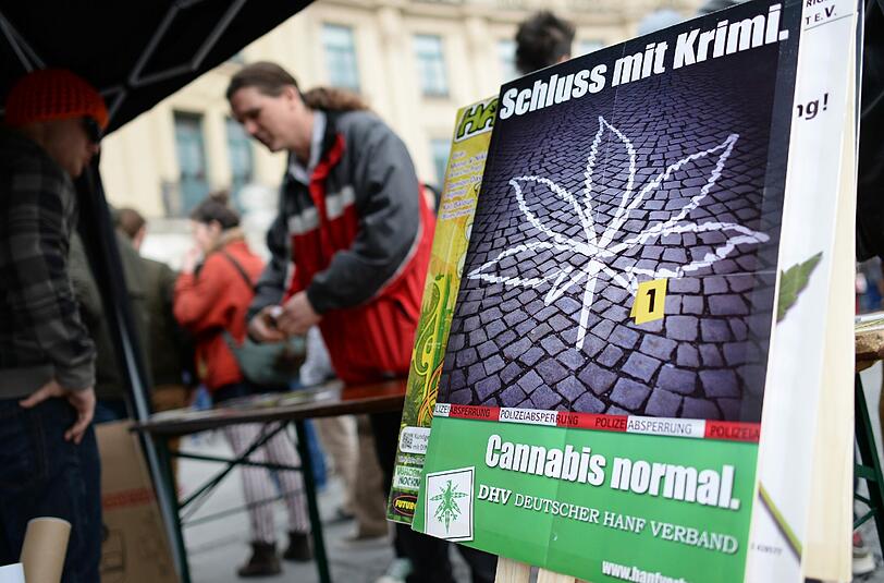 Teilnehmer einer Kundgebung des Deutschen Hanfverbandes stehen am 02.05.2015 hinter einem Plakat mit der Aufschrift "Schluss mit Krimi. Cannabis normal." auf dem Stachus in München.