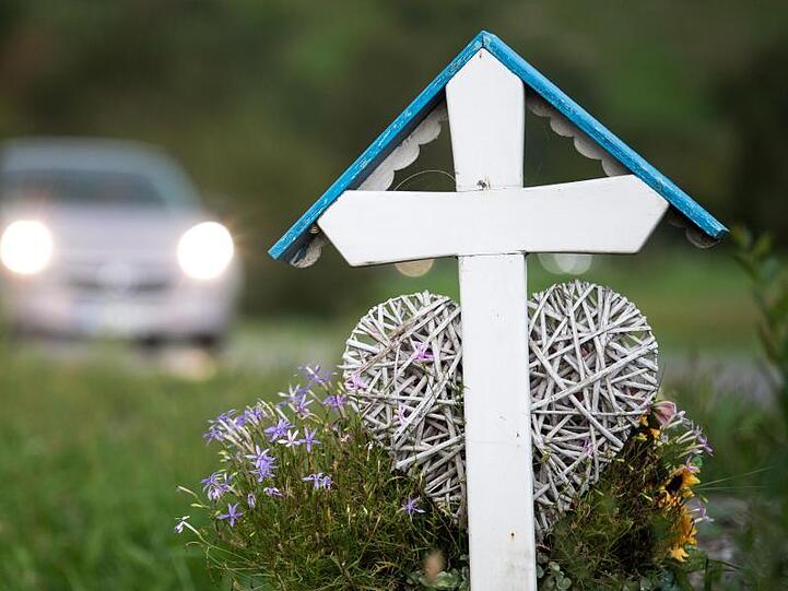 Autos fahren an einem weißen Kreuz für eine Unfalltote vorbei. Im ersten Quartal 2019 sind auf deutschen Straßen 633 Menschen gestorben.