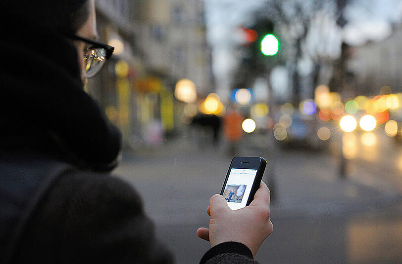 SmombieMenschen, die wie gebannt mit dem Handy über die Straße gehen und nicht gucken, wohin sie gehen, Zusammensetzung von Smartphone und Zombie.
