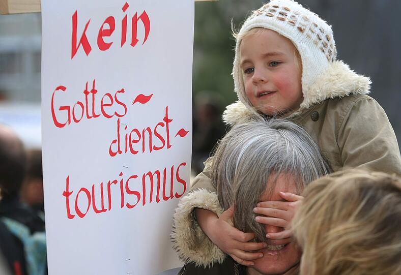 Katholiken stehen am Samstag (21.04.2012) mit Transparenten auf dem Domplatz von Augsburg (Schwaben). Im Rahmen einer Kundgebung demonstrieren sie gegen die geplante Pastoralreform des Bistums Augsburg.
