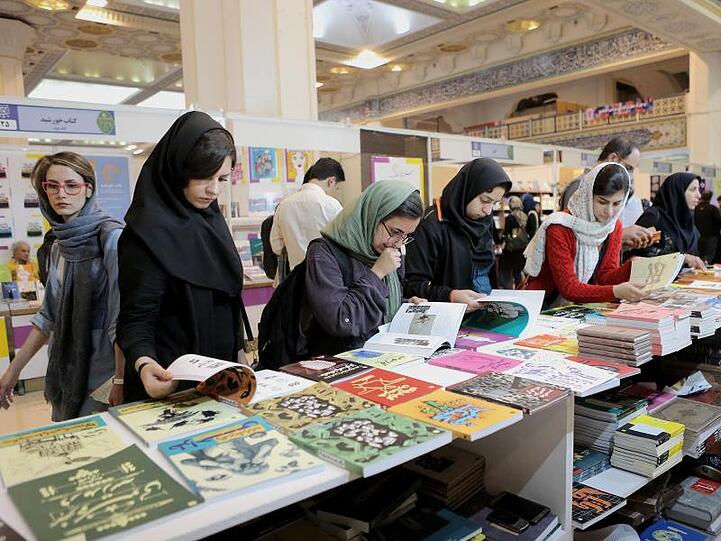 Frauen mit Kopftuch besuchen eine Buchmesse in Teheran. Im Iran müssen Mädchen ab neun Jahren in der Öffentlichkeit ein Kopftuch sowie einen langen, weiten Mantel tragen, um Haare und Körperkonturen zu verhüllen.