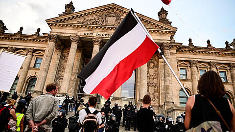 Ein Bild vom vergangenen Samstag: Teilnehmer einer Kundgebung gegen die Corona-Maßnahmen stehen vor dem Reichstag, ein Teilnehmer hält eine Reichsflagge.