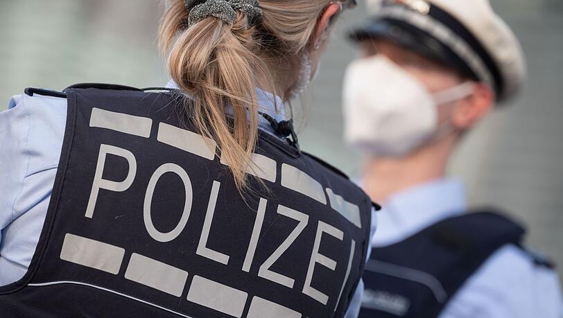 Eine Polizistin und ein Polizist mit FFP2-Maske stehen sich gegenüber.
