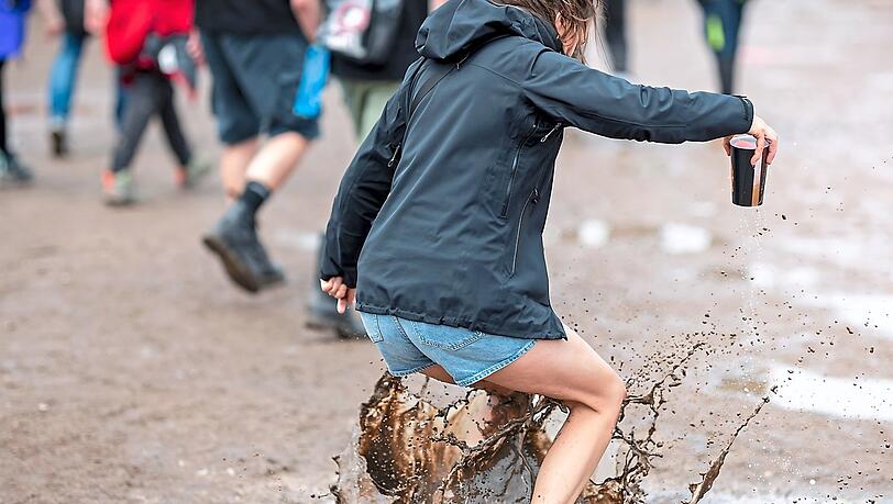 Eine Besucherin des Open-Air-Festivals springt in eine Pfütze. Foto: Daniel Karmann/dpa Eine Besucherin des Open-Air-Festivals springt in eine Pfütze. Foto: Daniel Karmann/dpa