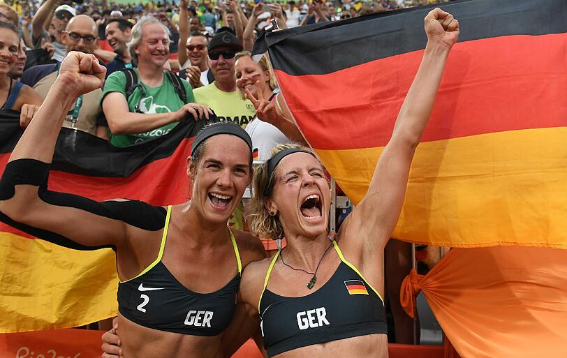 Deutsche Flaggen an der Copacabana: Kira Walkenhorst (l.) und Laura Ludwig feiern ihren Olympia-Halbfinalsieg gegen die Lokalmatadoren aus Brasilien.